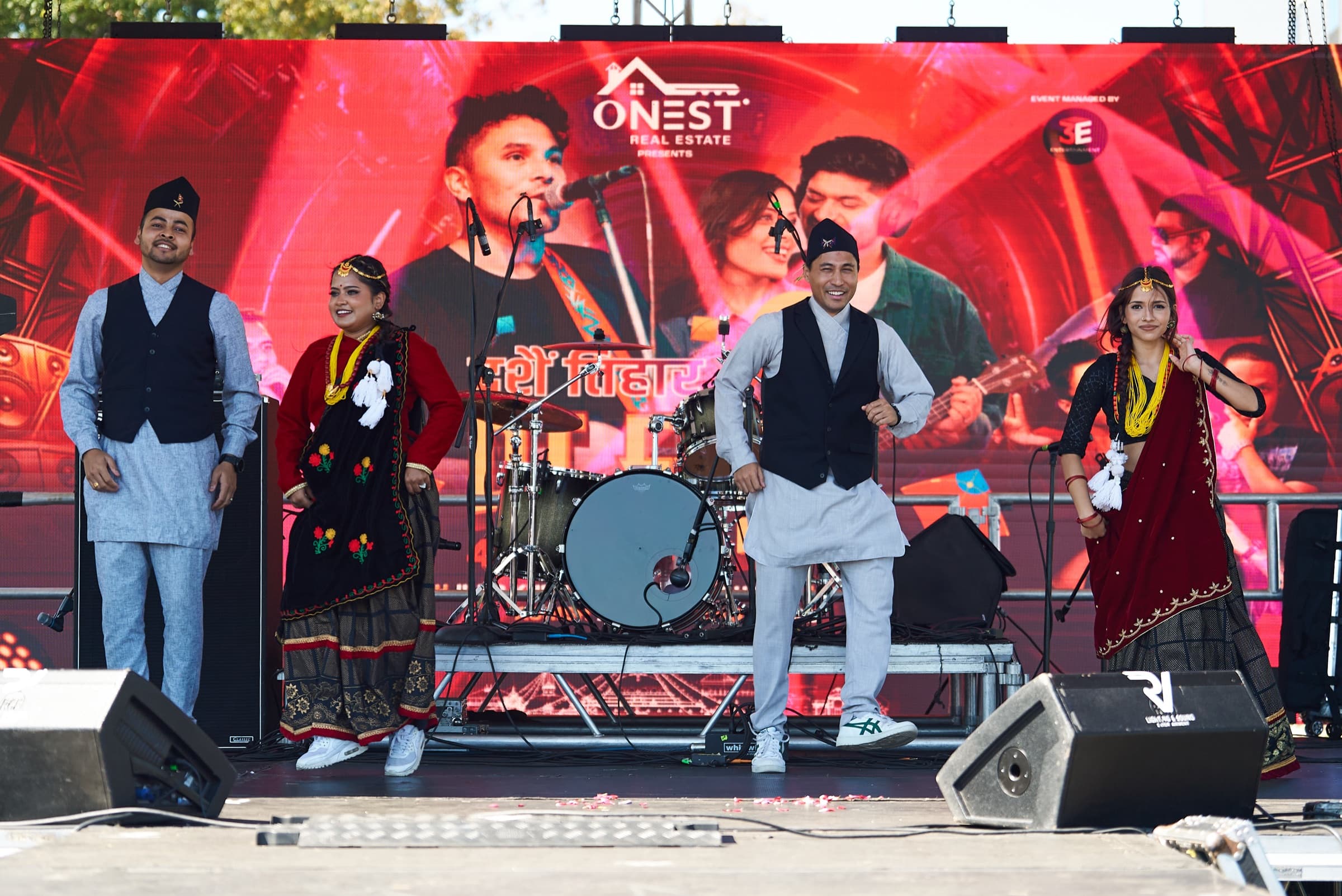 Folk dancers in traditional attire with drummers on stage